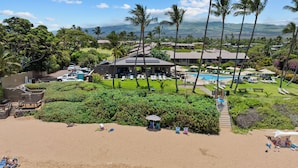 A resort with a pool, lounge chairs, and a beach area.