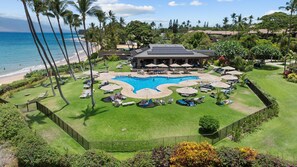 A resort with a central swimming pool, sun loungers, and a beach view.