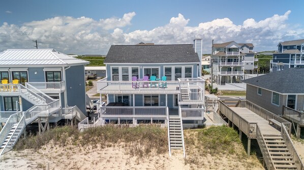 A beachfront property with multiple levels, outdoor seating, and a wooden deck. - Oceanfront Paradise with Amazing Views, Hot Tub! (Surf City)
