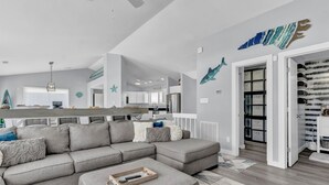 A modern living room with a grey sectional sofa, a wooden coffee table, and a kitchen in the background. - Oceanfront Paradise with Amazing Views, Hot Tub! (Surf City)