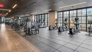 A gym with cardio machines, weight stations, and large windows offering city views. - Limoncello Spritz - Central Miami Pool Gym Spa (Miami)