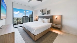 A modern bedroom with a large bed, a ceiling fan, a nightstand, and a view of the city through large windows. - Limoncello Spritz - Central Miami Pool Gym Spa (Miami)