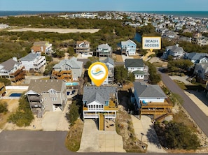 Área residencial com casas, piscina e placa indicando acesso à praia.