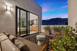 A modern balcony with a sofa, a dining table, and potted plants. - Sky Loft - Relax Poolside in Palm Springs (Palm Springs)