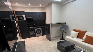 Un salon moderne avec un canapé, une table basse et un coin cuisine à l’arrière-plan.