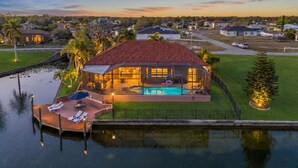 A house with a swimming pool, surrounded by a dock and a small water body. - Heated Pool, Game Room, & Dock on Freshwater Canal - Mermaid Cove - Roelens (Cape Coral)
