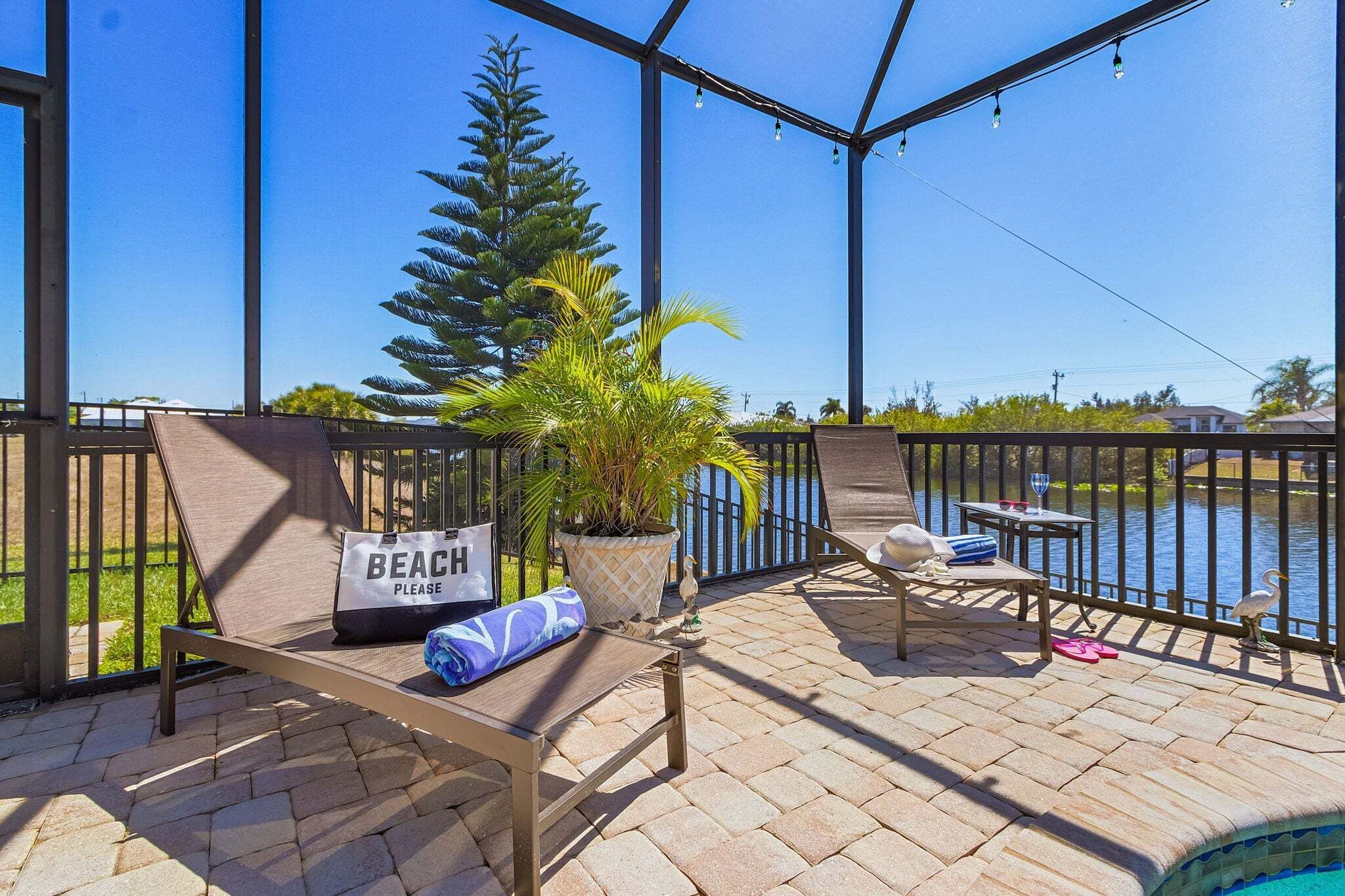 A covered outdoor area with a pool, lounge chairs, a bench, and a sign that reads "BEACH PLEASE".