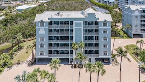 A multi-story hotel with a central courtyard, surrounded by palm trees and a view of the water.