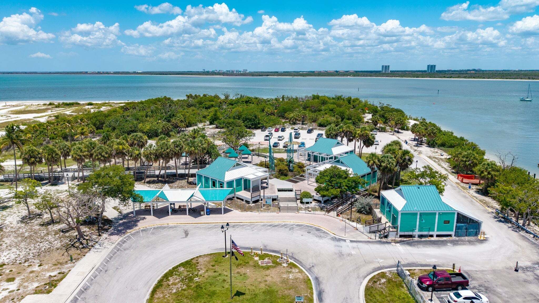 A coastal property with multiple buildings, a parking area, and a beach.