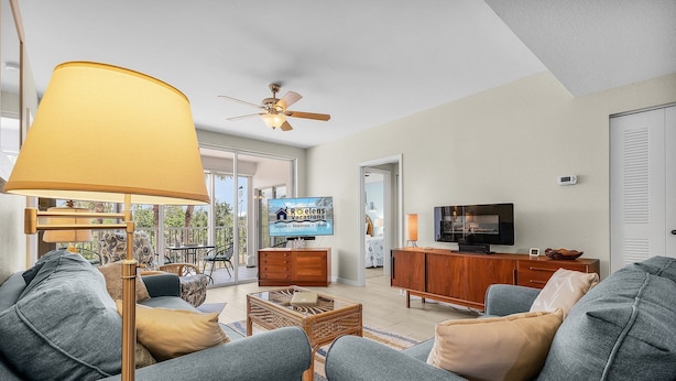 A modern living room with a sofa, a coffee table, a TV, and a ceiling fan.