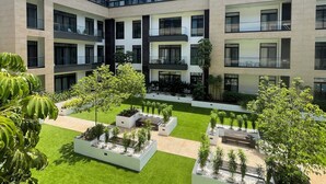 Un edificio moderno de varios pisos con un patio que cuenta con césped y jardineras.