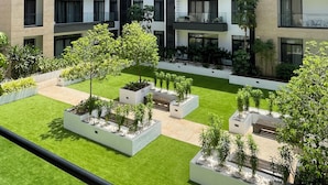 Un edificio moderno de varios pisos con un patio que cuenta con áreas ajardinadas y plantas en macetas.