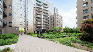 Un moderno edificio de apartamentos con un patio central, senderos pavimentados y abundante vegetación.