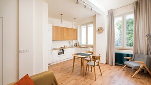 Une cuisine moderne avec des meubles en bois, une table à manger avec des chaises et une vue sur l’extérieur grâce à de grandes fenêtres.