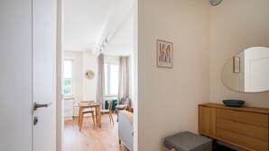 Une pièce moderne avec un plancher en bois, un banc gris, une armoire en bois et un grand miroir.