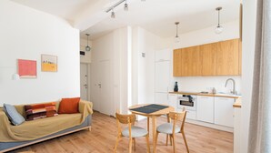 Un salon moderne comprenant un canapé, une table basse et une table à manger avec des chaises. On y trouve également un coin cuisine avec des meubles en bois et un évier.