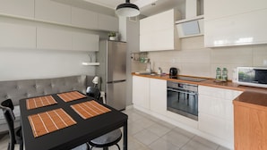 Et moderne køkken med spiseplads, med et sort bord, grå sofa og rustfrie stålemmer.