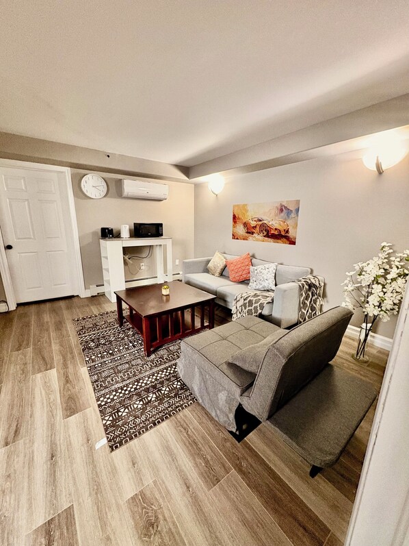 Een moderne woonkamer met een bank, salontafel en een kamerkleed met dessin.