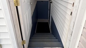 Eine schmale Treppe führt zu einer Tür mit Messingknauf, begrenzt von weißem Verkleidungsmaterial und einer blauen Wand.
