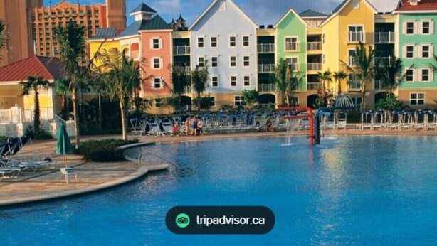 Un resort con edificios de colores, una piscina y sillones de descanso.