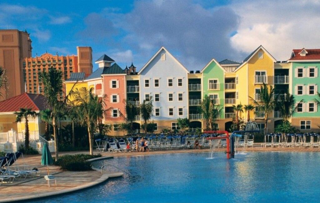 Um resort com edifícios coloridos, uma piscina e espreguiçadeiras.
