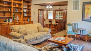 A spacious living room with a large sofa, a coffee table, and a bookshelf filled with books and decorative items.