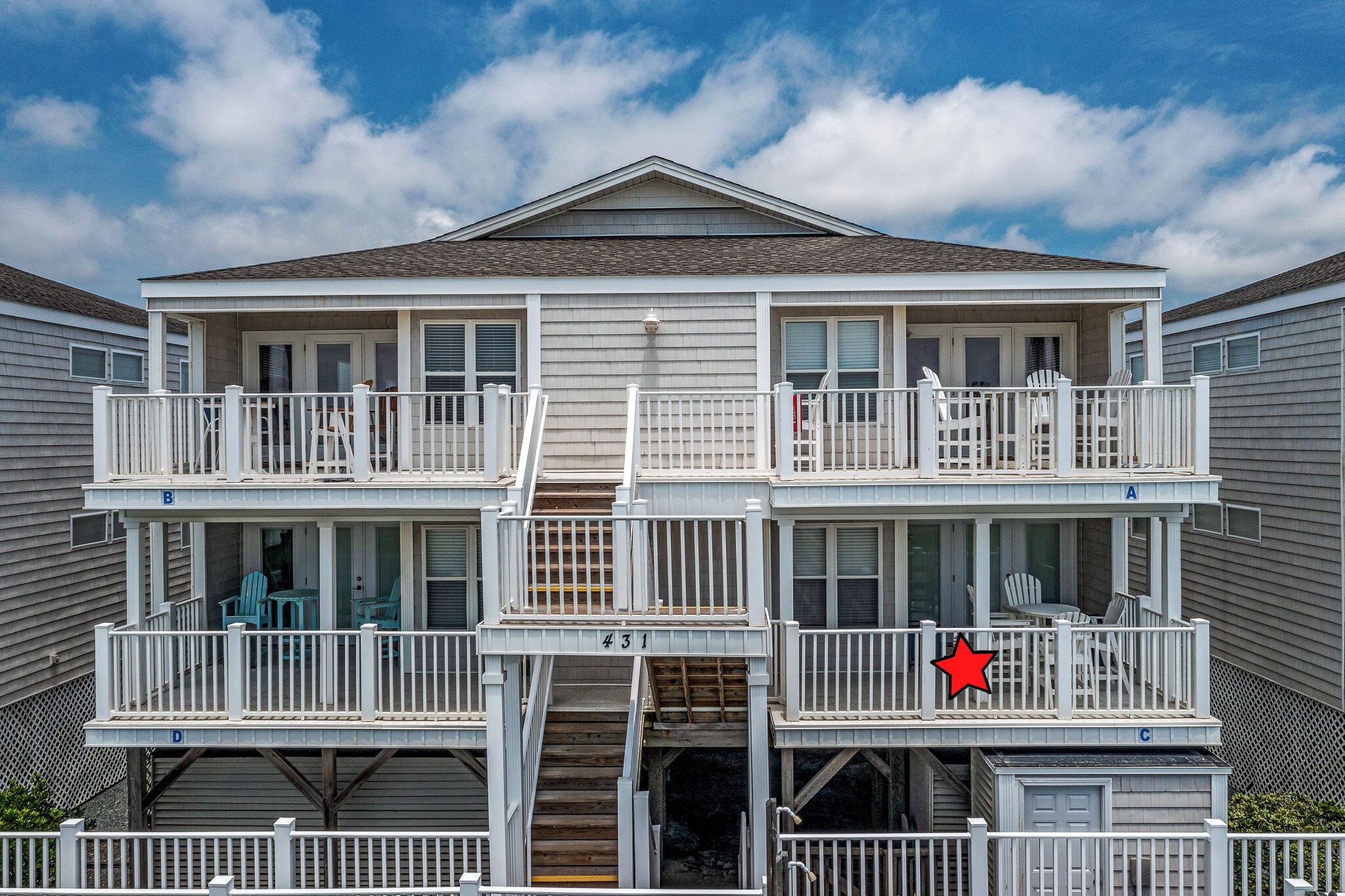 A two-story building with balconies, a staircase, and a number 431 sign.