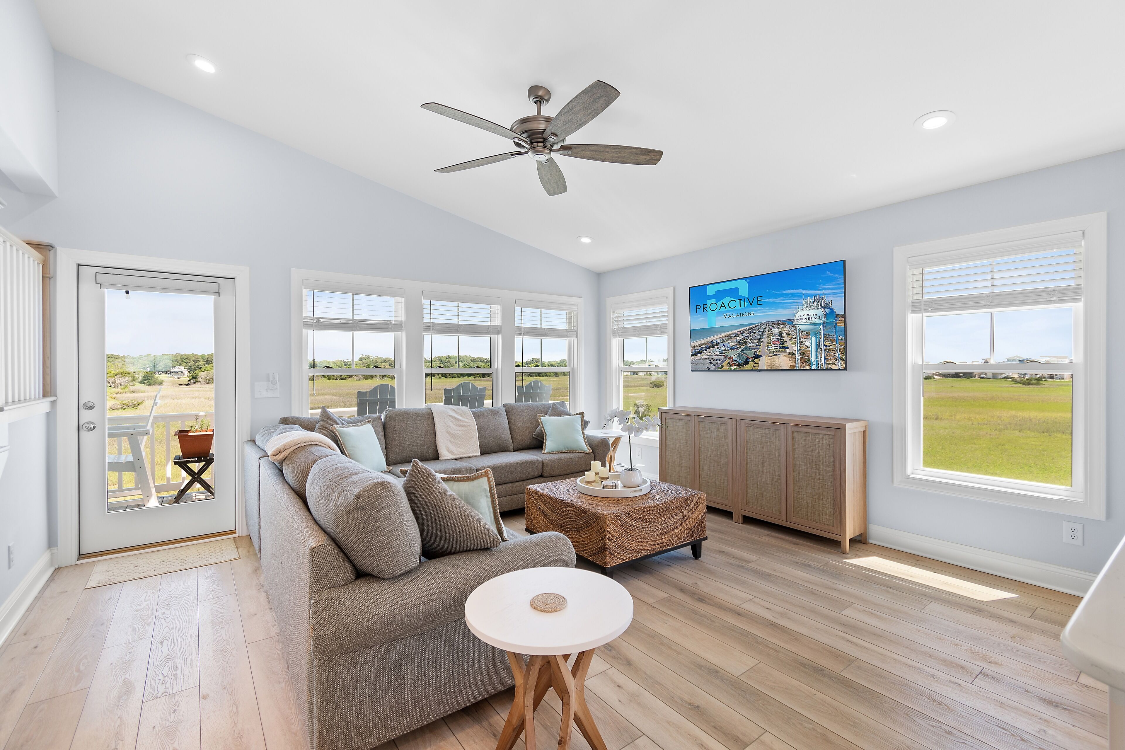 A spacious living room with a large sofa, a round coffee table, and a ceiling fan.