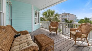 A covered porch with wicker furniture, including a sofa and chairs, and a small table.
