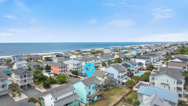 A coastal residential area with multiple two-story houses, a beach, and a clear sky.
