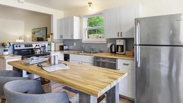 Una cocina moderna con una isla central, electrodomésticos de acero inoxidable y vistas al exterior.
