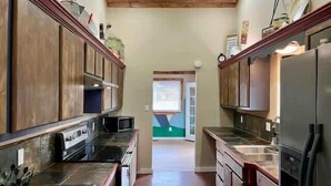 A narrow kitchen with wooden cabinets, a microwave, and a refrigerator.