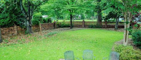 A patio with four metal chairs and a brick pathway.