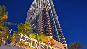Un edificio moderno e slanciato con un grande cartello con la scritta 'PALMS' alla base.