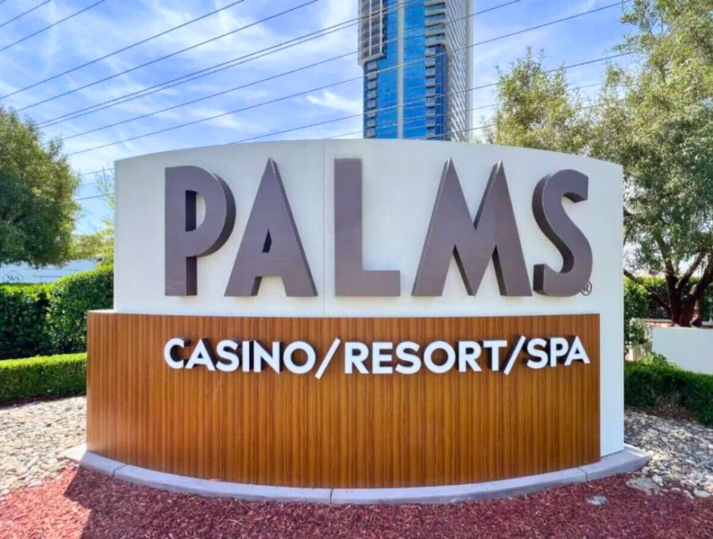 Letrero de 'PALMS Casino/Resort/Spa' con un diseño moderno y un edificio alto al fondo.