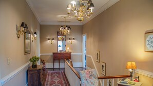 A hallway with a wooden bench, a small table with a lamp, and a staircase with a railing.