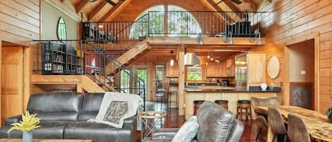 Un intérieur spacieux de chalet en bois, comprenant un salon, un coin repas et une cuisine.
