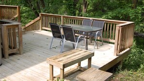 Eine Holzterrasse mit Tisch und Stühlen, umgeben von üppiger Vegetation.