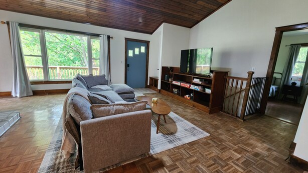 Ein geräumiges Wohnzimmer mit einem großen Sofa, einem Couchtisch und einem Fernseher auf einem Holzboden.
