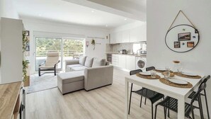 Un appartement moderne comprenant un coin repas, une cuisine et un salon avec un canapé et un fauteuil.