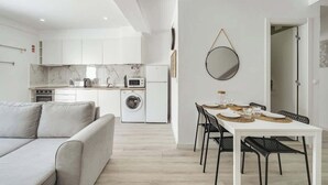 Une cuisine moderne avec des meubles blancs, un four encastré et un lave-linge.