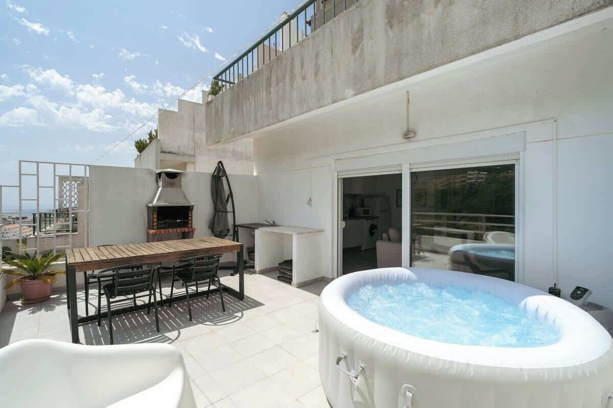 Terraza en la azotea con jacuzzi, mobiliario de exterior y zona de barbacoa.