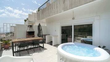 Terraza en la azotea con jacuzzi, mobiliario de exterior y zona de barbacoa.