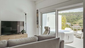 Un salon moderne doté d’un téléviseur à écran plat, d’un canapé et d’un balcon avec un jacuzzi et un espace salon extérieur.