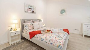A neatly arranged bedroom with a bed, bedside tables, a lamp, and artwork on the walls. - Charming Mezzanine Studio by HostWise (Porto)