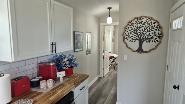 A kitchen with white cabinets, a wooden countertop, and a coffee maker. - Liberty Nook Tiny Home (Big Cabin)