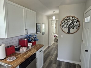 A kitchen with white cabinets, a wooden countertop, and a coffee maker.