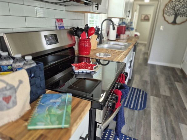 A kitchen with a stainless steel range, a microwave, and a built-in oven. There is a red pot holder and a blue towel on the counter.