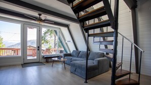 A modern living room with a grey sofa, a small round table, and a staircase with a metal railing.