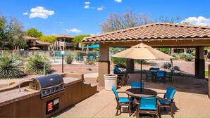 Un espace extérieur aménagé en terrasse, avec un barbecue, des sièges et une partie abritée.